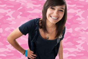 Young smiling woman wearing braces in front of pink camo background