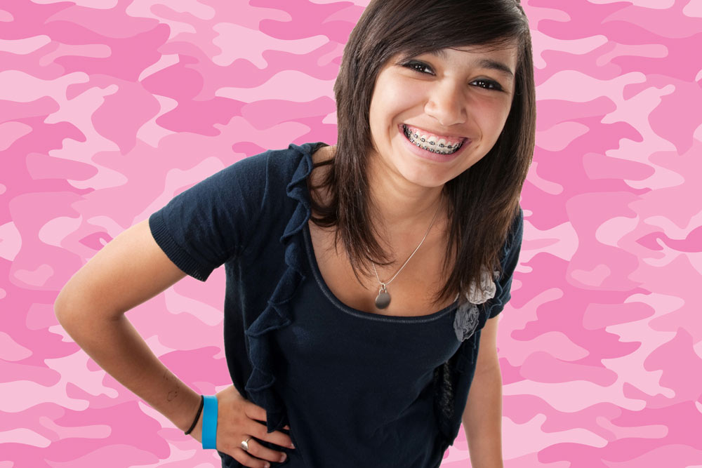 Young smiling woman wearing braces in front of pink camo background