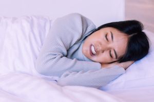 Young woman displaying bruxism symptoms while sleeping