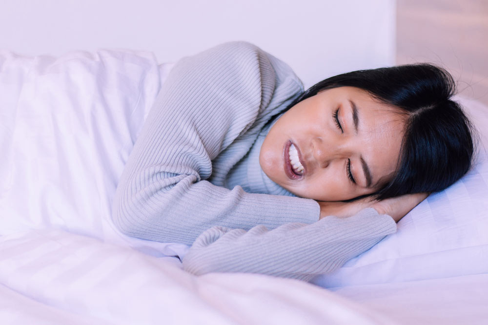 Young woman displaying bruxism symptoms while sleeping